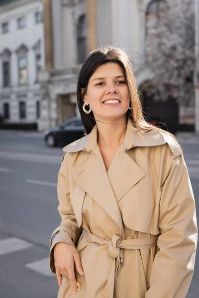Cheerful woman in elegant coat smiling on street in vienna — Stock Photo