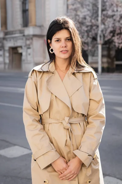 Brunette woman in elegant beige coat standing on street in vienna — Stock Photo