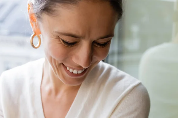 Nahaufnahme Porträt einer Frau mit Ring-Ohrring, die zu Hause auf verschwommenem Hintergrund lächelt — Stockfoto