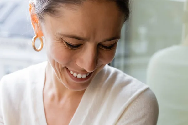 Close up portrait of woman in ring earring smiling at home on blurred background - foto de stock