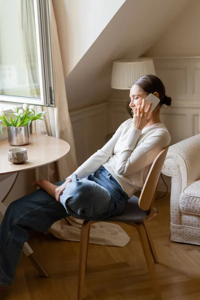 Frau in Jeans sitzt neben frischen Tulpen und telefoniert — Stockfoto