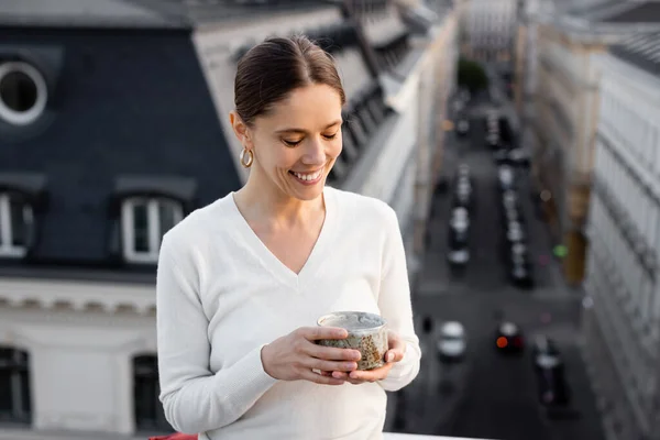 Femme gaie en pull blanc tenant tasse d'argile avec thé à l'extérieur — Photo de stock