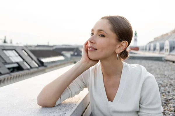 Nachdenkliche Frau lächelt, während sie auf dem Dach wegschaut — Stockfoto