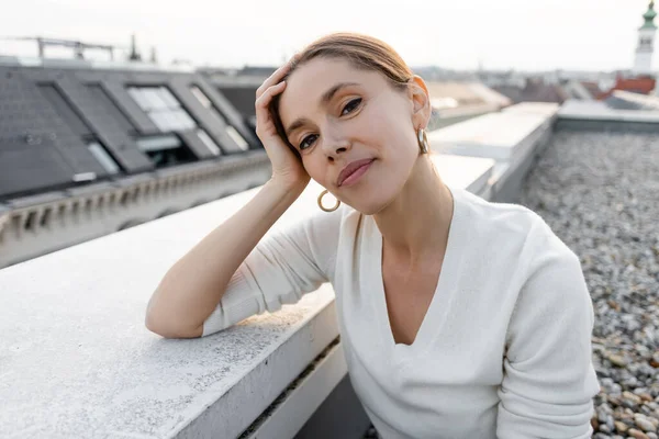 Positive woman looking at camera on rooftop of urban building — Fotografia de Stock