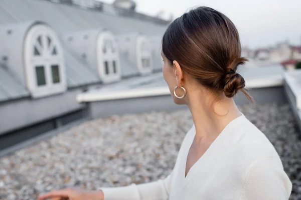 Mulher em anel brinco no telhado do edifício borrado — Fotografia de Stock