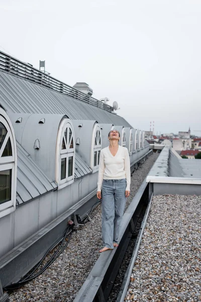 Full length of amazed woman looking up while walking barefoot on rooftop — Fotografia de Stock