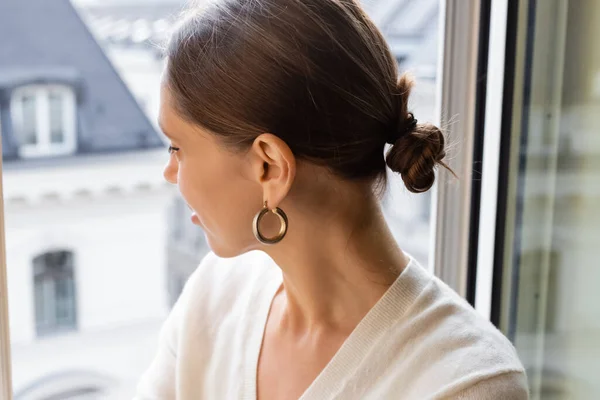 Woman in ring earring looking out window at home — Foto stock