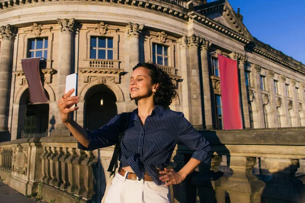 Happy young tourist taking selfie near famous building on museum island — Stockfoto