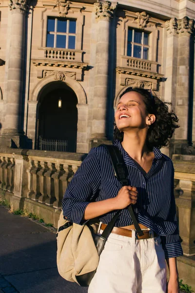 Sunshine on face of pleased young woman with backpack near bode museum in berlin — Photo de stock