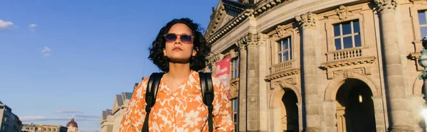 Stylish young woman in sunglasses standing near building on museum island, banner — Foto stock