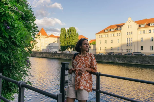 Curly woman in summer outfit standing near river in berlin — Stock Photo