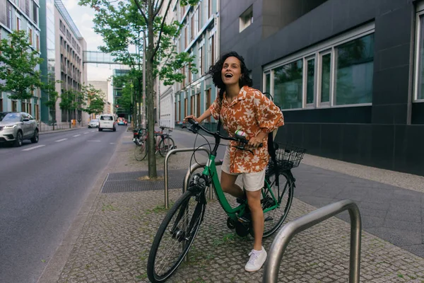 Full length of amazed young woman in summer outfit riding bicycle in berlin — Photo de stock