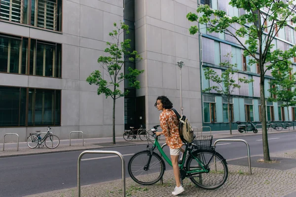 Full length of amazed young woman in summer outfit riding bicycle in berlin — Photo de stock