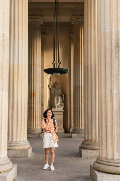 Amazed traveler with backpack standing near ancient columns and statue in berlin — Fotografia de Stock