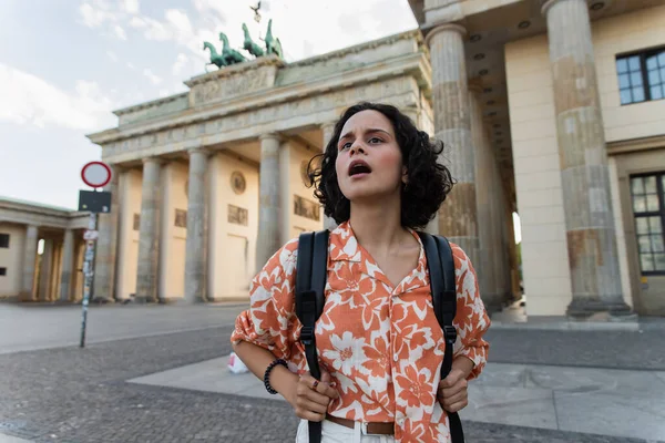 Surprised tourist with backpack standing near brandenburg gate in berlin — Photo de stock