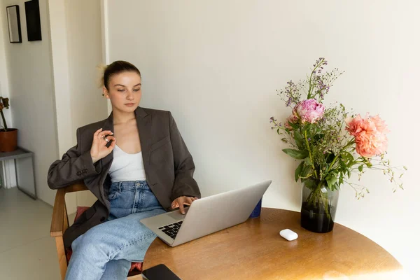 Жінка в куртці показує добре жест при використанні ноутбука вдома — стокове фото