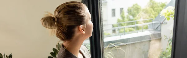 Mujer joven mirando a la puerta del balcón en casa, pancarta - foto de stock