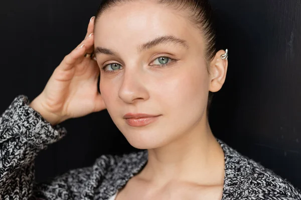 Portrait of woman in knitted cardigan looking at camera on black background — Stock Photo