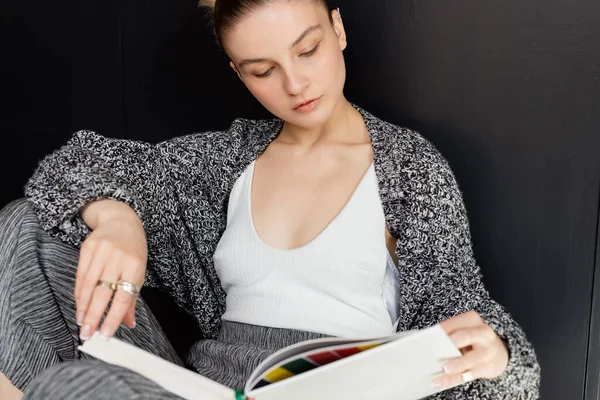 Giovane donna in maglia cardigan libro di lettura a casa — Foto stock