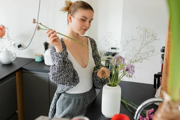 Frau in warmer Strickjacke bastelt Blumenstrauß in Vase zu Hause — Stockfoto