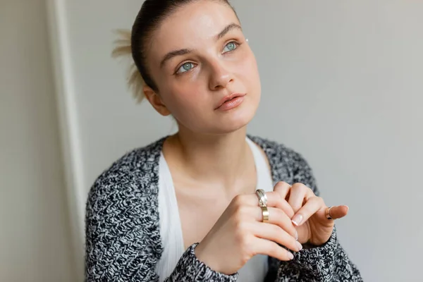 Dreamy young woman in knitted cardigan looking away at home — Stock Photo