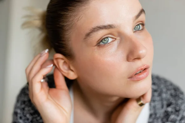 Portrait of young woman touching ear at home — Stock Photo