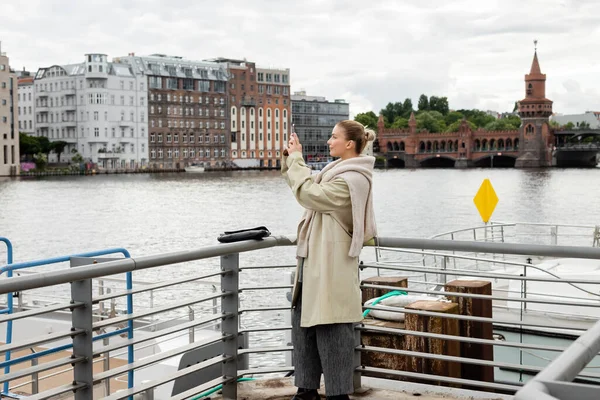 Side view of young woman taking photo on pier in Berlin — Stock Photo