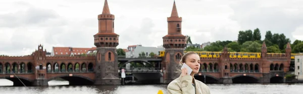 Mujer hablando por teléfono móvil con puente Oberbaum en el fondo en Berlín, pancarta - foto de stock