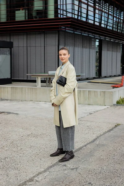 Stylish woman in trench coat looking at camera on urban street in Berlin — Stock Photo