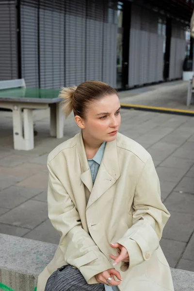 Woman in trench coat looking away on urban street in Berlin — Stock Photo