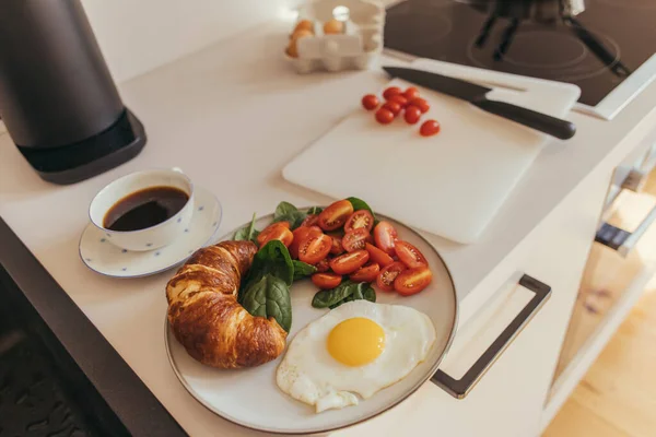 Deliziosa colazione con uova e croissant vicino al caffè in cucina — Foto stock