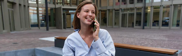 Mujer rubia en camisa hablando en teléfono inteligente en la calle urbana de Berlín, pancarta - foto de stock