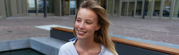 Femme blonde souriante regardant loin sur la rue urbaine, bannière — Photo de stock