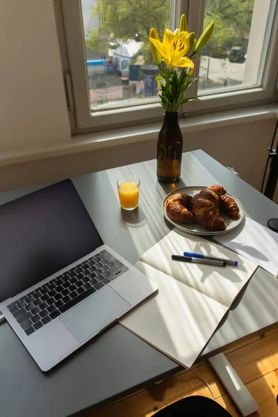 Flores perto do café da manhã e laptop na mesa em casa — Fotografia de Stock