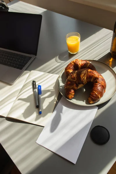 High angle view of croissants near laptop and orange juice on table at home — Stock Photo