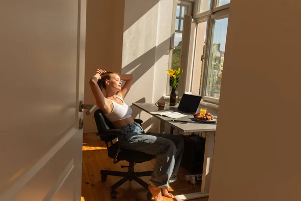 Young blonde woman touching hair near devices with blank screen and breakfast at home — Stock Photo