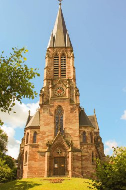 Mavi gökyüzüne karşı siyah ve kırmızı saati olan kilise.