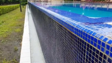 4k video, havuz dokusunun mavi arka planı küçük mavi mozaik fayanslar, açık havuzdan gelen su duvardan aşağı akıyor..