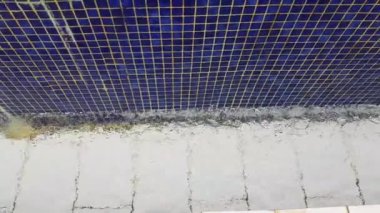 4k video, havuz dokusunun mavi arka planı küçük mavi mozaik fayanslar, açık havuzdan gelen su duvardan aşağı akıyor.