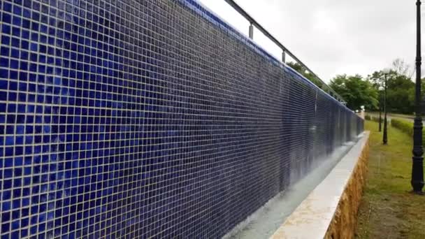 4k视频，一个蓝色水面的空旷室外游泳池的全景，蓝色背景纹理的小马赛克瓷砖，来自室外游泳池的水从墙上流下来 — 图库视频影像