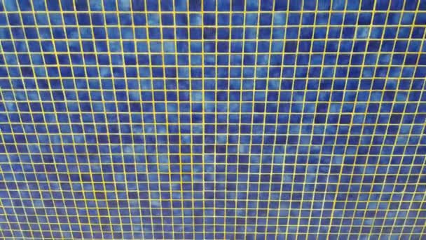 4k video, niebieskie tło tekstury basenu z małymi niebieskimi płytkami mozaikowymi, woda z odkrytego basenu spływa po ścianie — Wideo stockowe