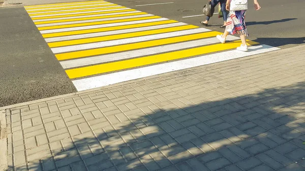 2人の歩行者が横断歩道の新しい黄色のマークで道路を横断生命安全輸送の概念 — ストック写真