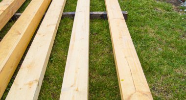 Çimlerin üzerinde yeni tahta tahtalar. Banliyö inşaatı için kereste.