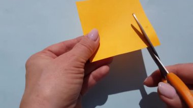 4k video. Turuncu kağıdı küçük makasla kesen kadın ellerinin yakın çekimi