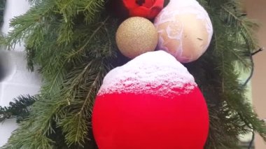 4K video, kırmızı ve altın topları bir Noel ağacına yakın plan, karla kaplı, açık havada. Noel ağacı süslemeleri ve çelenklerin arka planı