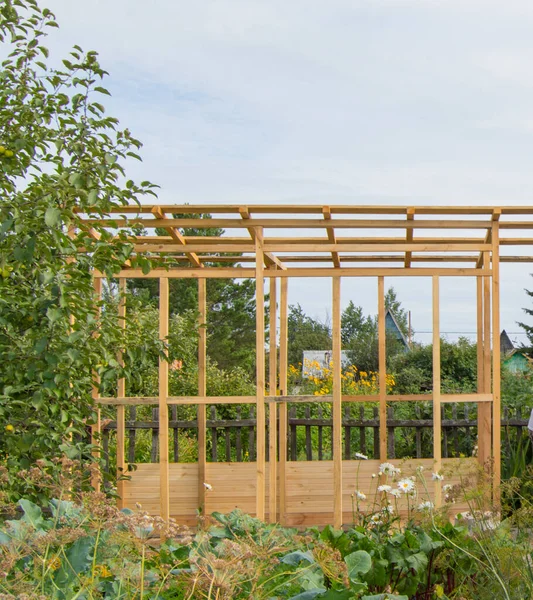 Wooden frame construction of a new veranda or gazebo on the territory of a country plot, in summer, outdoors.