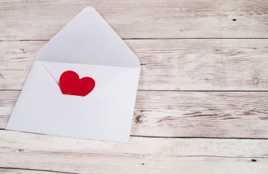 Ahşap zemin üzerinde kırmızı bir kalp olan boş bir zarf, sağdaki boşluğun bir kopyası..