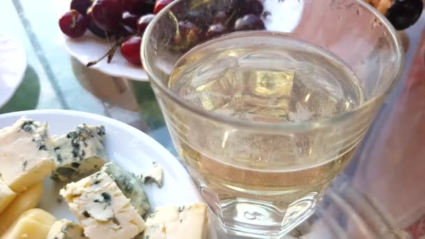 4Kビデオ 女性の手は テーブルの上にチェリーベリーの背景に白い輝くワインのプレートとガラスから金型で柔らかいチーズを取ります — ストック動画