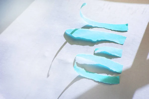 Streszczenie niebieskie podarte paski papieru na białym tle z cieniem światła słonecznego — Zdjęcie stockowe