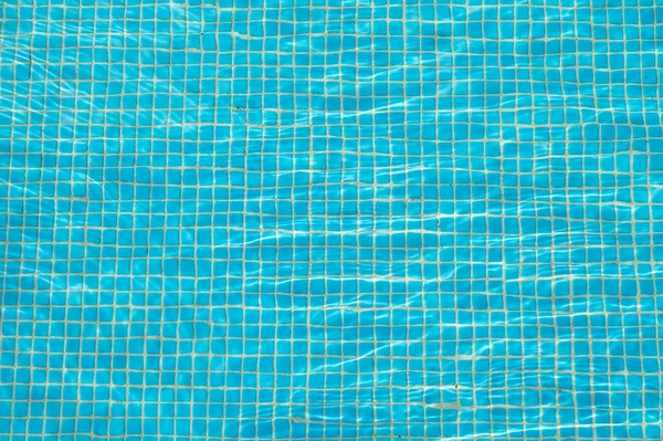 Blue pool water with sun glare, background and texture of water with mosaic tiles — Stock Photo, Image